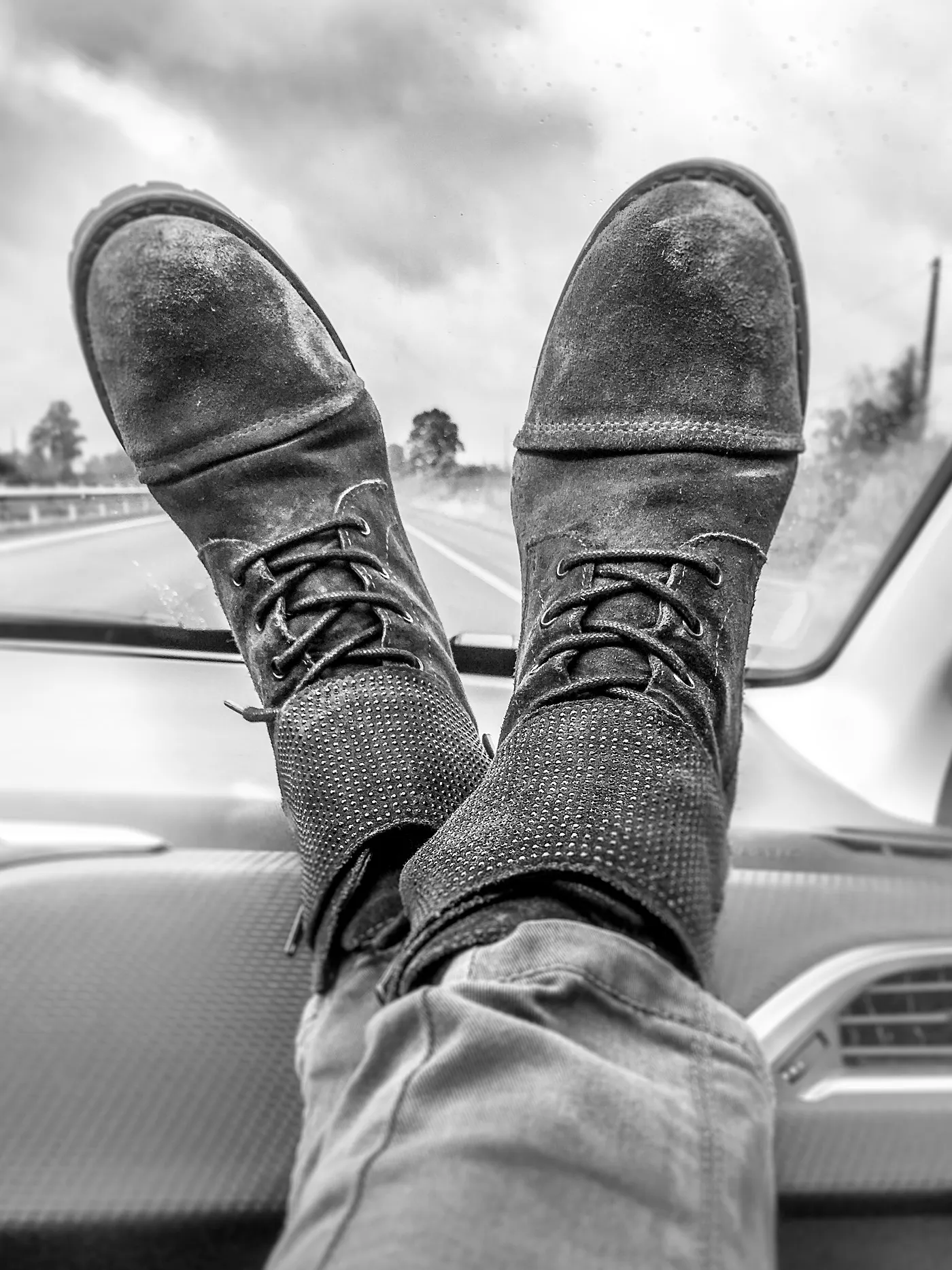 Grayscale Photography of Person's Feet on Vehicle Dashboard