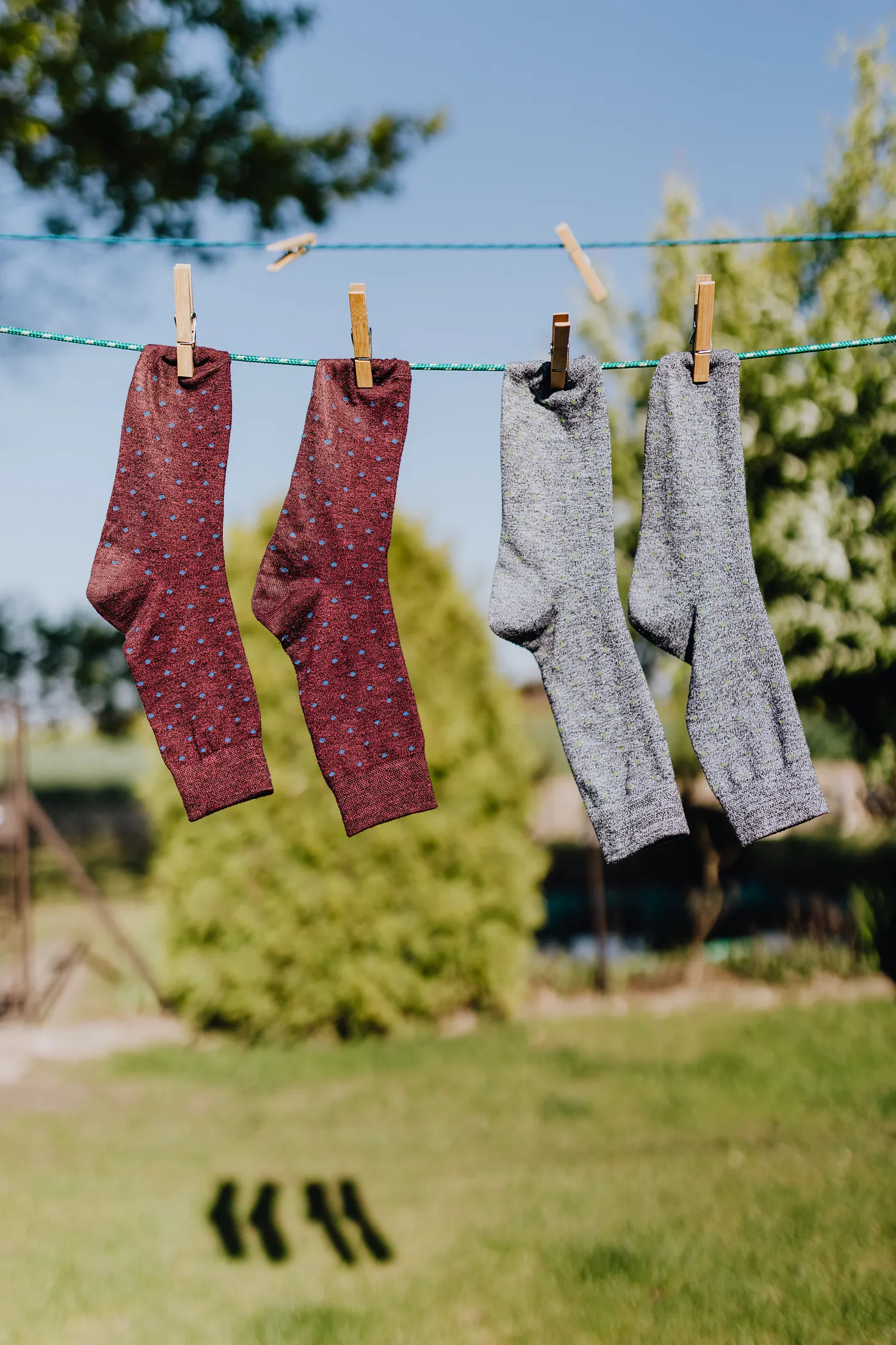 Multicolored socks drying on rope with clothespins in garden